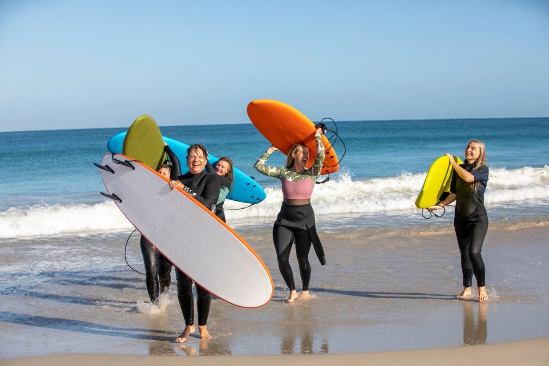 Group surf lesson on a Cascais beach — Day 3 of BTQ Events corporate incentive trip with rashguards, longboards on the Atlantic coast at Cascais