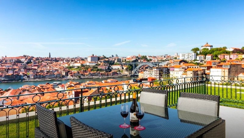 The Yeatman terrace dining table set for an intimate seated dinner with the Luiz I Bridge framing the Douro behind, used by BTQ Events as an alfresco format for senior-tier private dinners and press-launch evenings